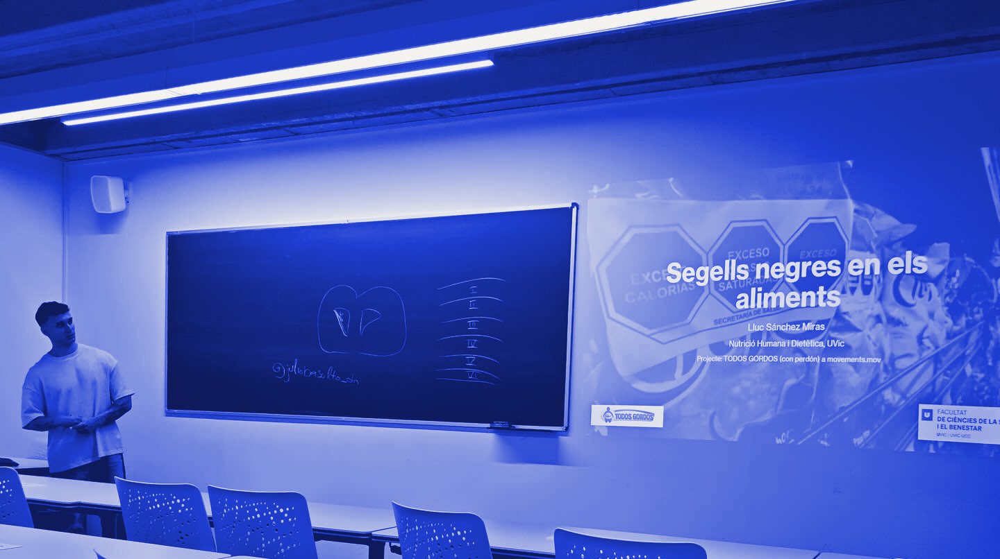 Lluc Sánchez dando la charla Segells negres en els aliments en un aula de la Universitat de Vic